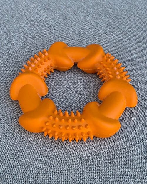 Orange spiky rubber chew ring on gray fabric
