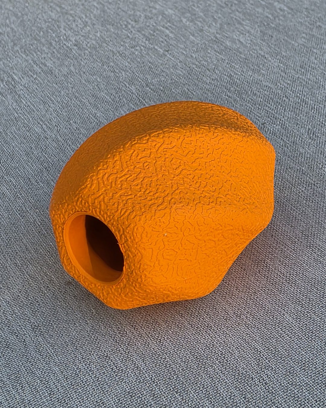 Orange textured rubber treat ball with a hole for treats